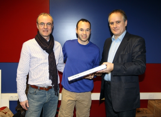 Denis Chaumier, a la dreta, entregant el Gran Llibre dels 50 anys de la Pilota d'Or a Iniesta. A l'esquerra, el redactor de 'France Football' Vincent Machenaud. Foto: Miguel Ruiz (FCB)